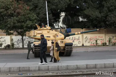 Egyptians walk pass the wire barricade as Egyptian army soldiers and tanks guard the presidental palace in Cairo December 19, 2012. Opponents of Egyptian President Mohamed Mursi staged protests in Cairo on Tuesday agains...
