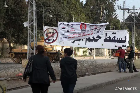 Egyptians walk pass the wire barricade as Egyptian army soldiers and tanks guard the presidental palace in Cairo December 19, 2012. Opponents of Egyptian President Mohamed Mursi staged protests in Cairo on Tuesday agains...