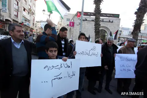 Palestinians hold placards during a protest in solidarity with Palestinian in al-Yarmouk refugee camp in Syria in the West Bank city of Ramallah on 19 December 2012. Pro-rebel sources reported that at least 25 Palestinia...