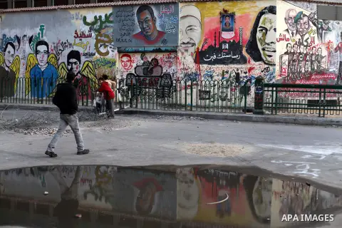 Egyptians opposition supporter stand at the presidential palace and anti-Morsi graffiti is seen on the palace's wall behind him in Cairo, Dec. 18, 2012. Egypt's opposition staged rallies across the country on Tuesday to...