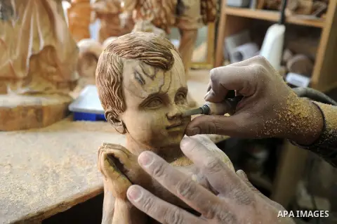 A Palestinian carpenter carves a wooden sculpture of baby Jesus at a workshop in the West Bank town of Bethlehem, on December 20, 2012. The traditional birthplace of Jesus Christ prepares to celebrate Christmas later thi...
