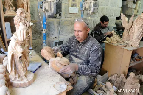 A Palestinian carpenter carves a wooden sculpture of baby Jesus at a workshop in the West Bank town of Bethlehem, on December 20, 2012. The traditional birthplace of Jesus Christ prepares to celebrate Christmas later thi...
