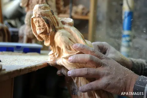 A Palestinian carpenter carves a wooden sculpture of baby Jesus at a workshop in the West Bank town of Bethlehem, on December 20, 2012. The traditional birthplace of Jesus Christ prepares to celebrate Christmas later thi...