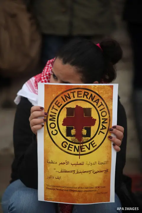 Palestinian protesters hold posters and a sign reading "ICRC, do your work or leave" during a demonstration in support of Palestinian prisoners held in Israeli jails, some of whom are observing a hunger strike, outside t...