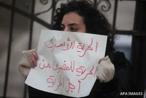 Palestinian protesters hold posters and a sign reading "ICRC, do your work or leave" during a demonstration in support of Palestinian prisoners held in Israeli jails, some of whom are observing a hunger strike, outside t...