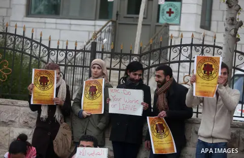 Palestinian protesters hold posters and a sign reading "ICRC, do your work or leave" during a demonstration in support of Palestinian prisoners held in Israeli jails, some of whom are observing a hunger strike, outside t...
