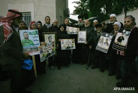 Palestinians hold pictures of prisoners held in Israeli jails during a sit-in outside the Red Cross offices in Jerusalem on December 20, 2012. in solidarity with hunger-striking detainees held by Israel to demand their r...