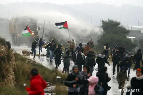Palestinian protesters run as an Israeli Army truck fires a water cannon, containing a foul-smelling substance, during clashes with stone-throwing protesters in the West Bank village of Nabi Saleh, near Ramallah December...