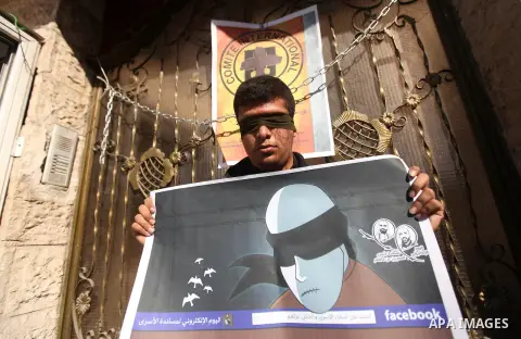 A Palestinian man who covered their eyes with black ribbons demonstrate in support of Palestinian prisoners held in Israeli jails, some of whom are observing a hunger strike, in Gaza City on December 22, 2012. Photo by M...