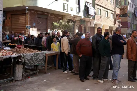 Egyptian men queue with other voters at a polling station during the second round of a referendum on a new draft constitution in Giza, south of Cairo, on December 22, 2012. Egyptians are voting in the final round of a re...