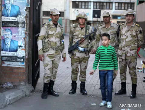 Members of Egyptian army stand guard at the entrance of the polling station, during the second round of a referendum for the new Egyptian constitution, in Giza, south of Cairo, Egypt, 22 December 2012. More than 25 milli...