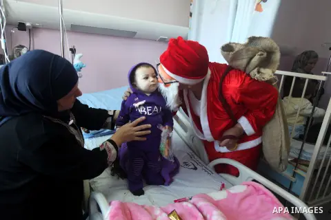 Palestinian Man dressed as Santa Claus give the Children a present in the hospital in the West Bank city of Ramallah on 23 December 2012 .Palestinian Christians across the Israeli occupied Palestinian West Bank are prepa...