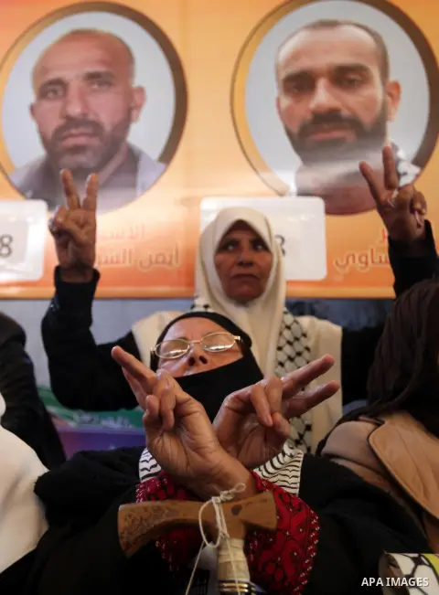 Palestinians hold pictures of prisoners held in the Israeli jails during a rally in Gaza city on December 24, 2012. in solidarity with hunger-striking detainees held by Israel to demand their release from detention witho...