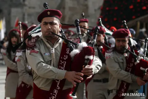 Palestinians celebrate around a Christmas tree at the Manger Square, outside the Church of the Nativity, in the West Bank town of Bethlehem, Sunday, Dec. 24, 2012. Thousands of Palestinians and tourists were flocking to...