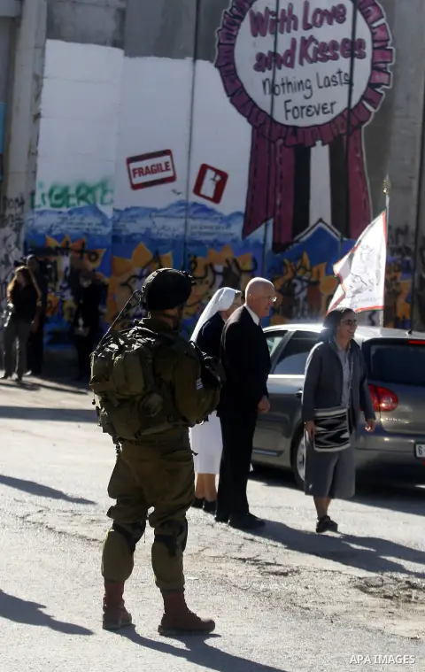 An Israeli soldiers stands guard as a convey of cars transporting the Latin Patriarch of Jerusalem Fouad Twal cross through an Israeli checkpoint to the West Bank city of Bethlehem December 24, 2012. Twal crossed from Je...