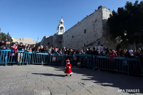Palestinians wait for the arrival of the Latin Patriarch of Jerusalem Fouad Twal outside the Church of the Nativity, the site revered as the birthplace of Jesus, in the West Bank city of Bethlehem December 24, 2012. Phot...