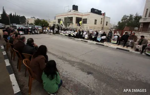 Palestinians hold pictures of prisoners held in Israeli jails during a sit-in outside the Red Crescent offices near the West Bank city of Ramallah, in solidarity with hunger-striking detainees held by Israel to demand th...