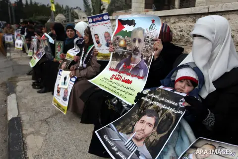 Palestinians hold pictures of prisoners held in Israeli jails during a sit-in outside the Red Crescent offices near the West Bank city of Ramallah, in solidarity with hunger-striking detainees held by Israel to demand th...