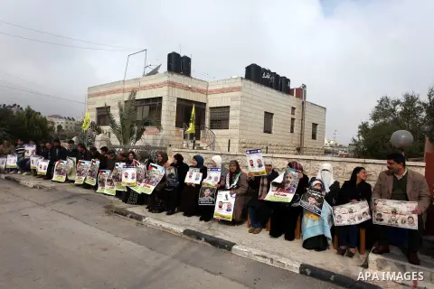Palestinians hold pictures of prisoners held in Israeli jails during a sit-in outside the Red Crescent offices near the West Bank city of Ramallah, in solidarity with hunger-striking detainees held by Israel to demand th...