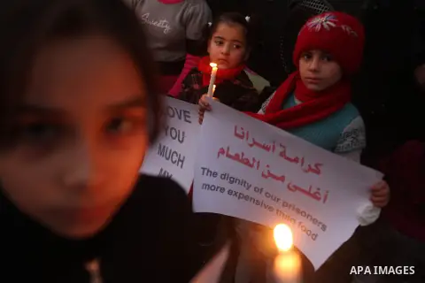 Palestinian children hold placards and candles during a candlelight rally in solidarity with hunger-striking detainees held by Israel in Gaza city to demand their release from detention without trial. December 25, 2012....