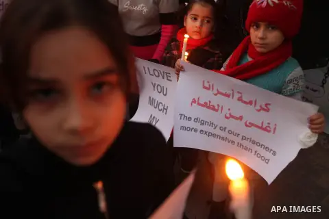 Palestinian children hold placards and candles during a candlelight rally in solidarity with hunger-striking detainees held by Israel in Gaza city to demand their release from detention without trial. December 25, 2012....