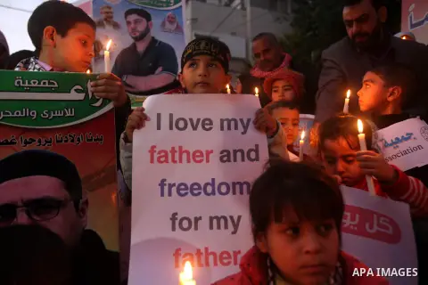 Palestinian children hold placards and candles during a candlelight rally in solidarity with hunger-striking detainees held by Israel in Gaza city to demand their release from detention without trial. December 25, 2012....