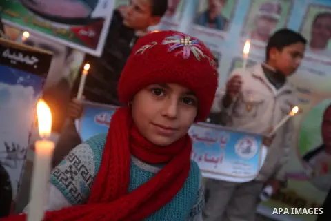 Palestinian children hold placards and candles during a candlelight rally in solidarity with hunger-striking detainees held by Israel in Gaza city to demand their release from detention without trial. December 25, 2012....