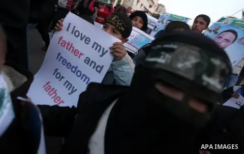 Palestinian children hold placards and candles during a candlelight rally in solidarity with hunger-striking detainees held by Israel in Gaza city to demand their release from detention without trial. December 25, 2012....