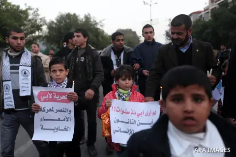Palestinian children hold placards and candles during a candlelight rally in solidarity with hunger-striking detainees held by Israel in Gaza city to demand their release from detention without trial. December 25, 2012....