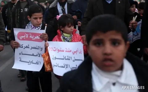 Palestinian children hold placards and candles during a candlelight rally in solidarity with hunger-striking detainees held by Israel in Gaza city to demand their release from detention without trial. December 25, 2012....