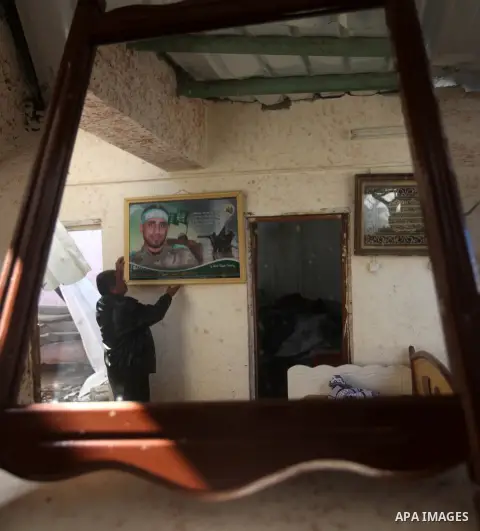 A Palestinian man puts a portrait of his killed son on the wall at his bombed house, marking the 4 th anniversary of his death during the Israel-Gaza war, in Gaza City, on Dec. 26, 2012. The three-week offensive dramatic...