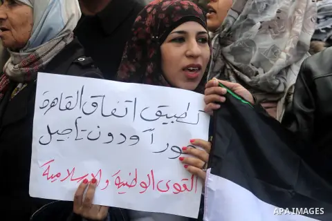 Palestinians hold placards and their national flags during a demonstration in the West Bank city of Ramallah calling for an end in the political division and commitment to the reconciliation agreement between rival Pales...
