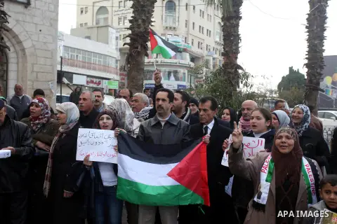Palestinians hold placards and their national flags during a demonstration in the West Bank city of Ramallah calling for an end in the political division and commitment to the reconciliation agreement between rival Pales...