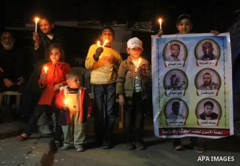 Palestinian children hold candles during a candlelight vigil in front of Red Cross offices, solidarity with hunger-striking detainees held by Israel in Gaza city to demand their release from detention without trial. Dece...