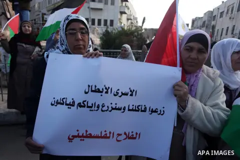 Palestinians hold placards and their national flags during a demonstration in the West Bank city of Ramallah calling for an end in the political division and commitment to the reconciliation agreement between rival Pales...