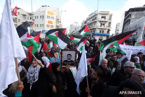 Palestinians hold placards and their national flags during a demonstration in the West Bank city of Ramallah calling for an end in the political division and commitment to the reconciliation agreement between rival Pales...