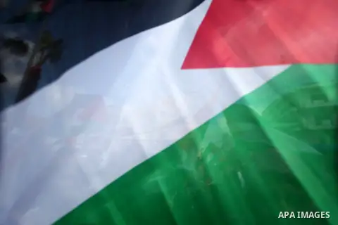 Palestinians hold placards and their national flags during a demonstration in the West Bank city of Ramallah calling for an end in the political division and commitment to the reconciliation agreement between rival Pales...