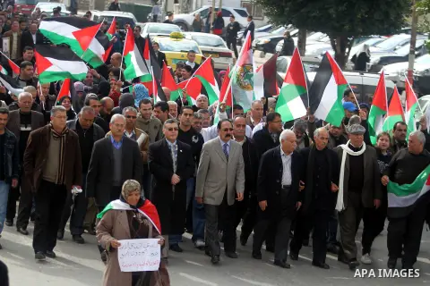 Palestinians hold placards and their national flags during a demonstration in the West Bank city of Ramallah calling for an end in the political division and commitment to the reconciliation agreement between rival Pales...