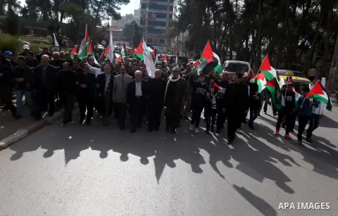 Palestinians hold placards and their national flags during a demonstration in the West Bank city of Ramallah calling for an end in the political division and commitment to the reconciliation agreement between rival Pales...