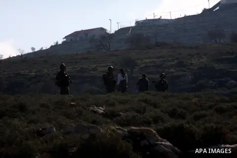 Israeli soldiers stand guard next to Israeli settlers from the Yetshar settlement after they attacked Palestinian farmers from the West Bank village of Qusra near the West Bank City of Nablus 27 December 2012. Photo by N...