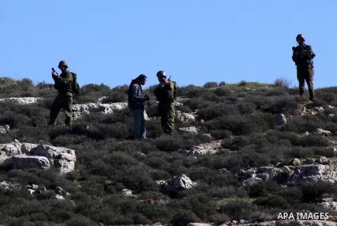An Israeli soldier stops a settler from he Yetshar settlement after settlers attacked Palestinian farmers from the West Bank village of Qusra near the West Bank City of Nablus 27 December 2012. Photo by Nedal Eshtayah