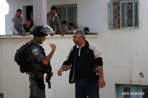 A Palestinian man speaks with an Israelii soldier, during a search carried out by Israeli soldiers after they raid the village of Urif, near Nablus, West Bank, 27 December 2012. Israeli soldiers raided the village after...
