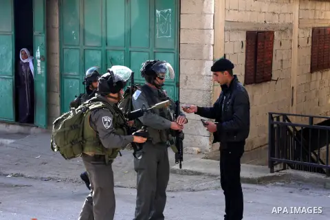 A Palestinian man shows his ID card to Israeli soldiers, during a search carried out by Israeli soldiers after they raid the village of Urif, near Nablus, West Bank, 27 December 2012. Israeli soldiers raided the village...