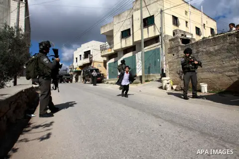 A Palestinian schoolgirl passes Israeli soldiers, during a search carried out by Israeli soldiers after they raid the village of Urif, near Nablus, West Bank, 27 December 2012. Israeli soldiers raided the village after c...