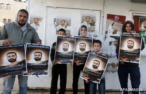 Palestinian protesters hold portraits of Samer Issawi, a Palestinian prisoner held in an Israeli jail and on hunger strike since August 1, during a solidarity sit-in outside the Red Cross offices in Jerusalem, on Dec. 27...