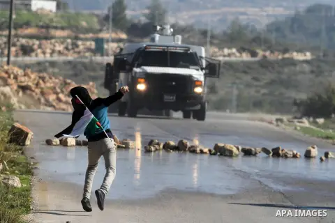 A Palestinian protester throws a stone at Israeli security officers during clashes at a protest against Jewish settlements, in the West Bank village of Nabi Saleh, near Ramallah December 28, 2012. Photo by Issam Rimawi