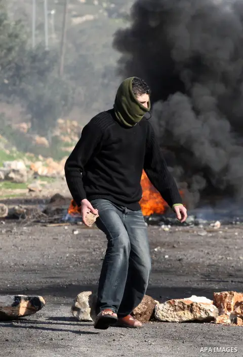 A Palestinian demonstrator throws stones at Israeli soldiers during clashes at the weekly protest against the Jewish settlement of Qadomem, near Nablus, West Bank, 28 December 2012. According to Palestinian sources, five...