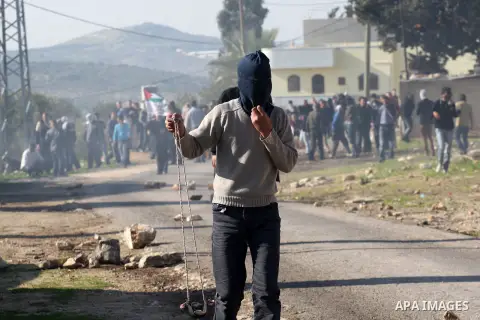 A Palestinian demonstrator hurls stones at Israeli soldiers during clashes at the weekly protest against the Jewish settlement of Qadomem, near Nablus, West Bank, 28 December 2012. According to Palestinian sources, five...