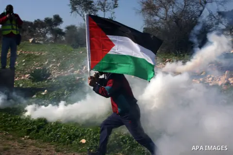 A Palestinian demonstrator runs cover from tear gas fired by Israeli soldiers during clashes at the weekly protest against the Jewish settlement of Qadomem, near Nablus, West Bank, 28 December 2012. According to Palestin...