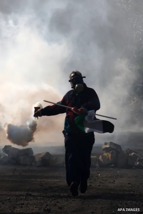 A palestinian demonstrator throws back a tear as canister fired by Israeli soldiers during clashes at the weekly protest against the Jewish settlement of Qadomem, near Nablus, West Bank, 28 December 2012. According to Pa...